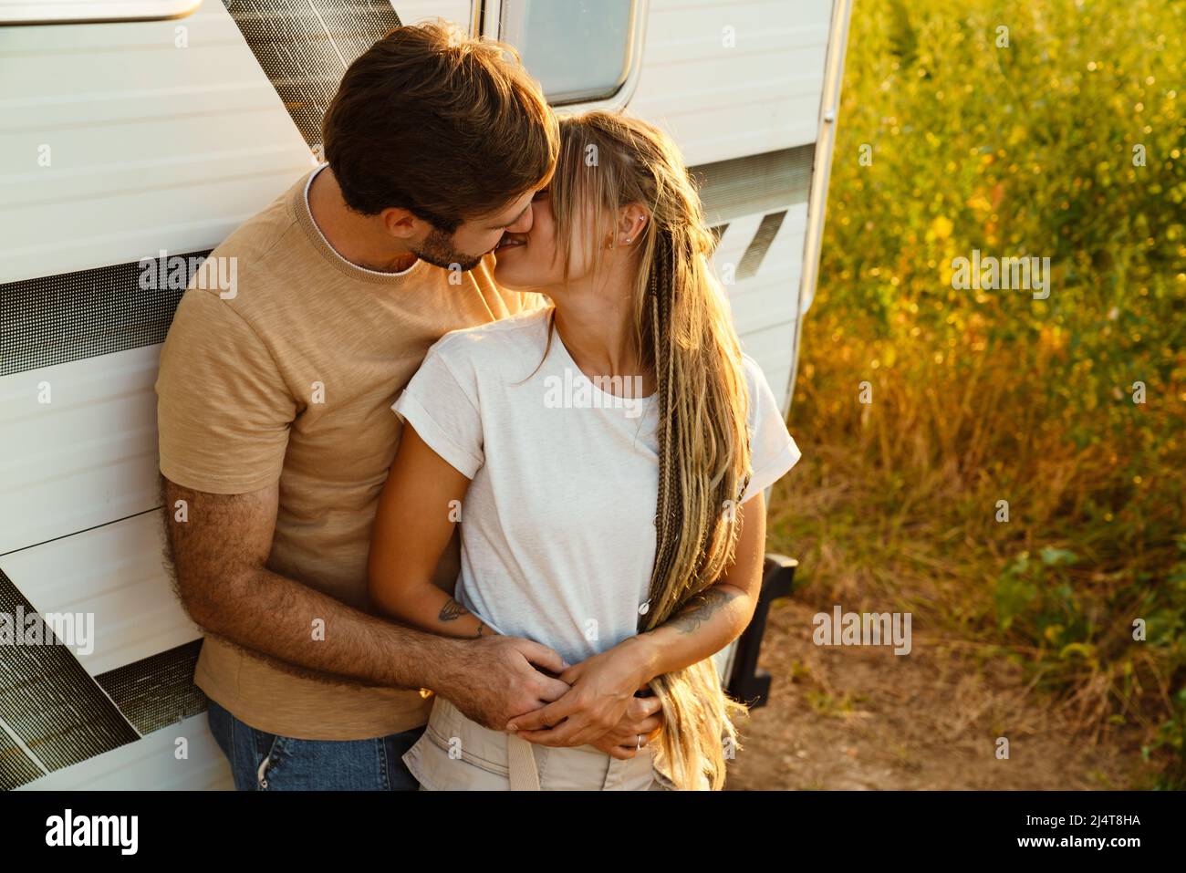 White couple hugging and kissing while standing by trailer outdoors