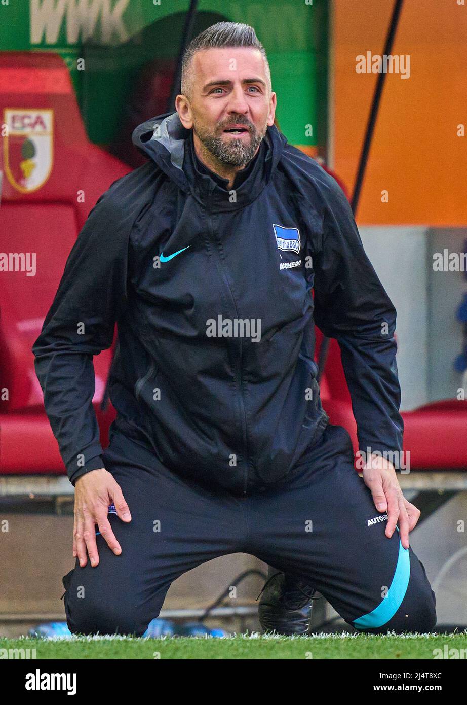 Vedad Ibisevic Hertha assistant coach kneeling in the grass  in the match FC AUGSBURG - HERTHA BSC BERLIN 0-1 1.German Football League on April 16, 2022 in Augsburg, Germany  Season 2021/2022, matchday 30, 1.Bundesliga, 30.Spieltag. © Peter Schatz / Alamy Live News    - DFL REGULATIONS PROHIBIT ANY USE OF PHOTOGRAPHS as IMAGE SEQUENCES and/or QUASI-VIDEO - Stock Photo