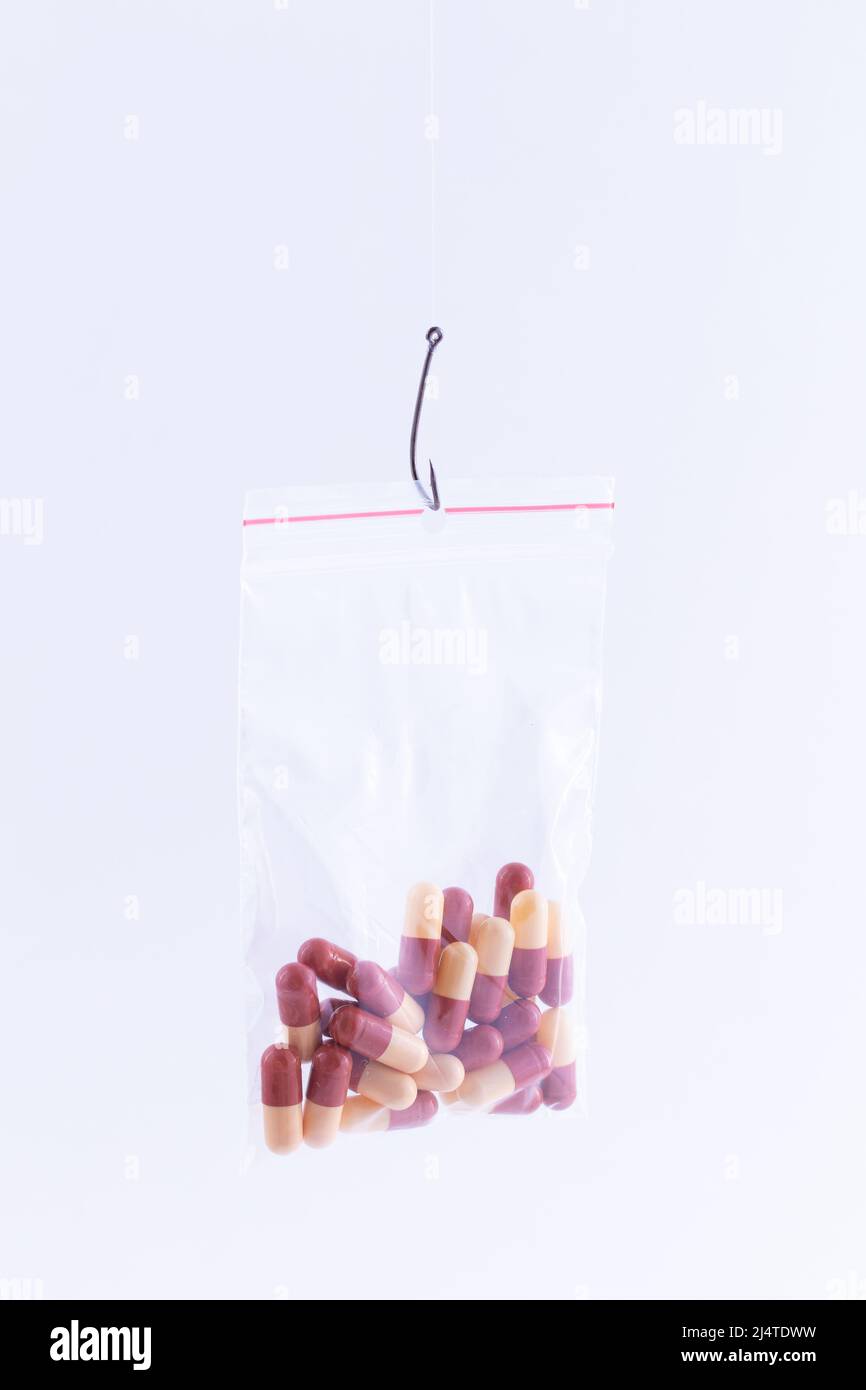 The Pharmaceutical Trap and Drug Addiction - Colored Pills or Tablets  Hanging in Small Ziplock Bag on a Fishing Hook Against the White Background  Stock Photo - Alamy