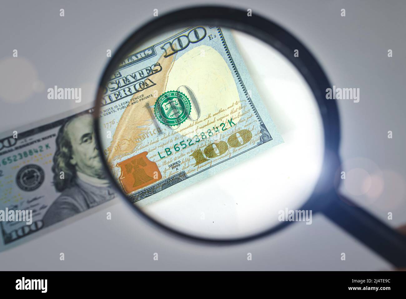 Zoom to money. Magnifying Glass - 100 US Dollars. Concept on the theme of checking money for authenticity Stock Photo