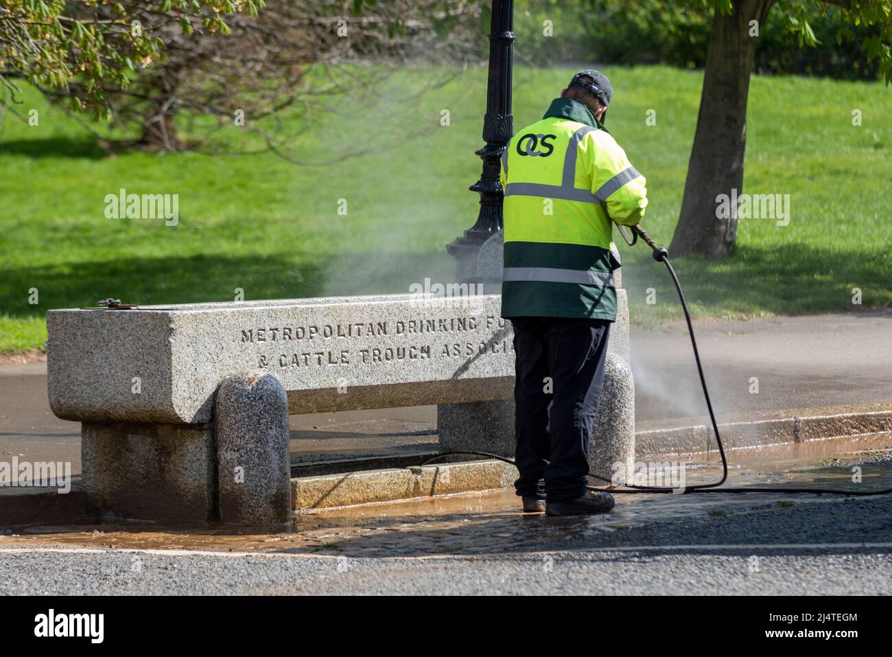 OCS Group ground maintenance employee jet washing horse and cattle drinking trough in Hyde Park, London, UK. International facilities management Stock Photo