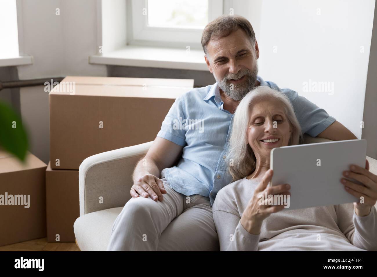 Older couple buy furniture for home using tablet on relocation Stock