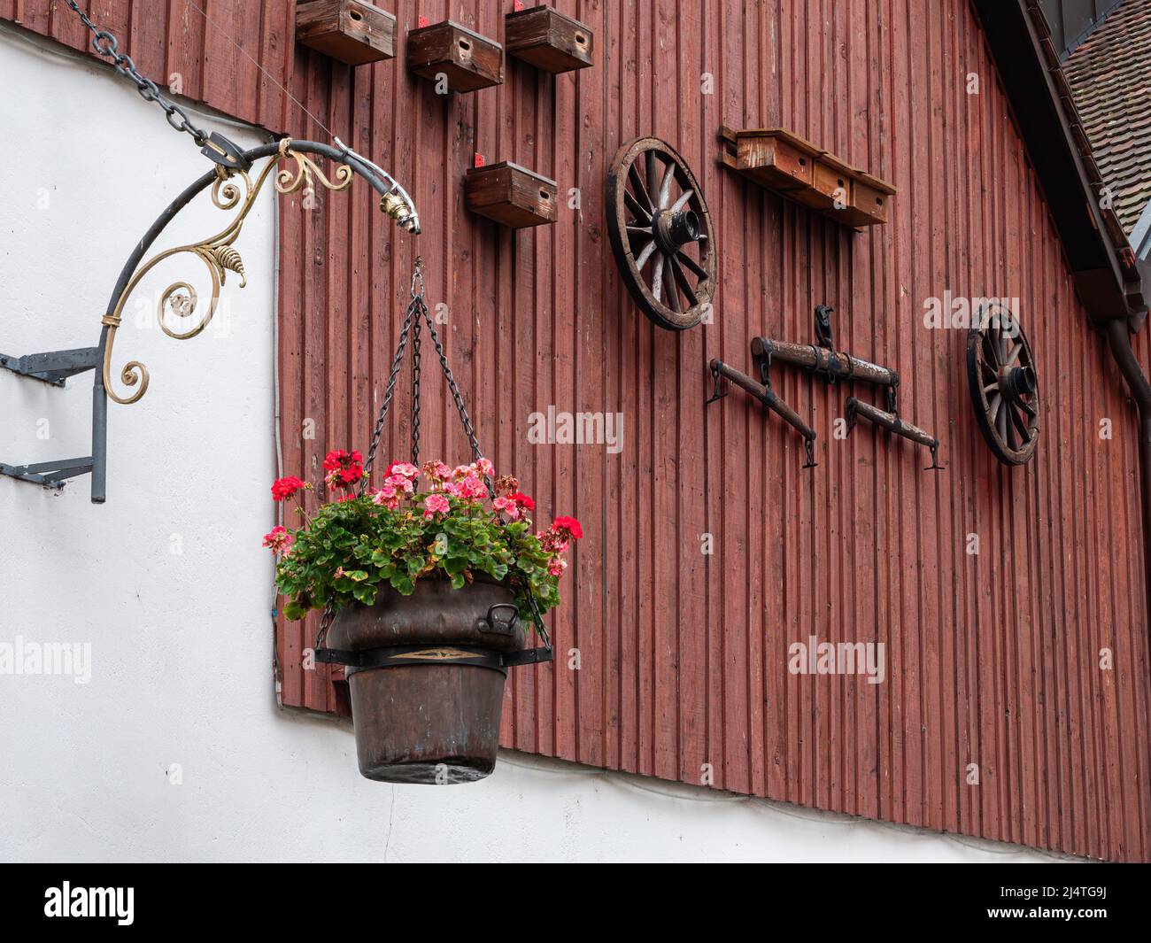 Flower pot, wheels and decorations of an old farmhouse facade in Laufen, Switzerland Stock Photo