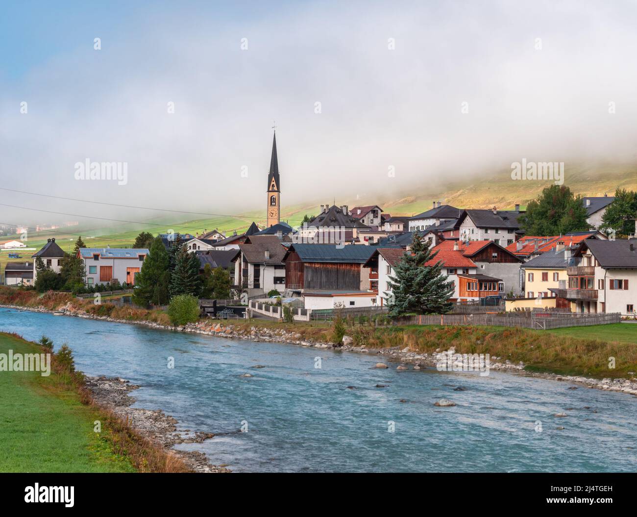 River Inn and village of Zuoz, municipality in the Maloja Region in the Swiss canton of Graubunden. Idyllic autumn foggy mood, Stock Photo