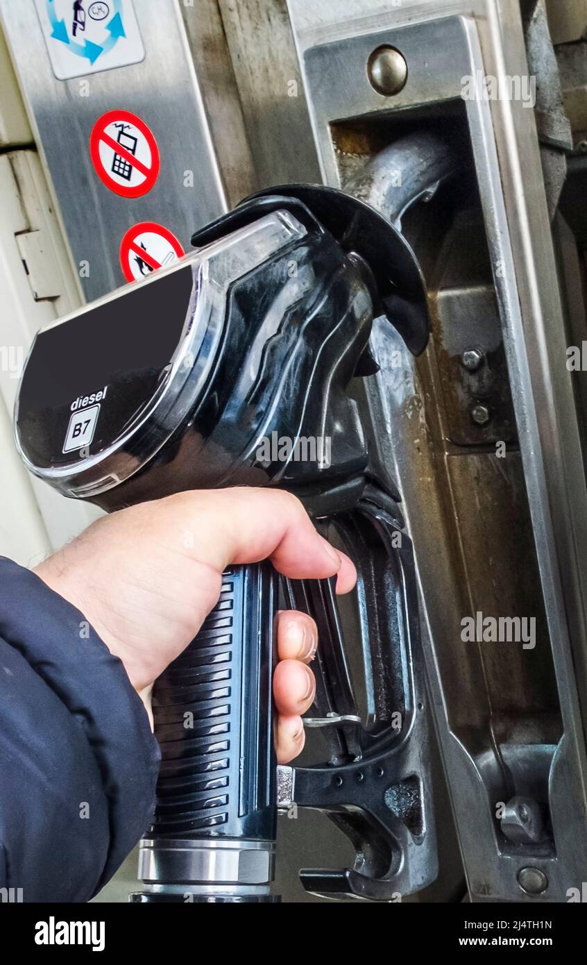 Gas station customer replacing a black B7 fuel pump nozzle after