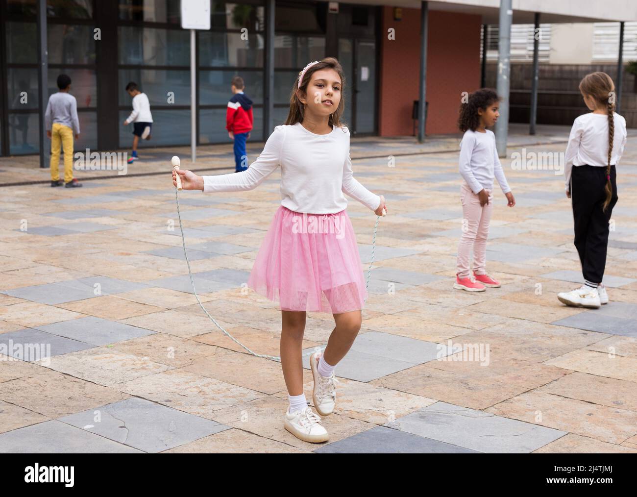 Happy tweenager girl skipping rope in schoolyard Stock Photo Alamy