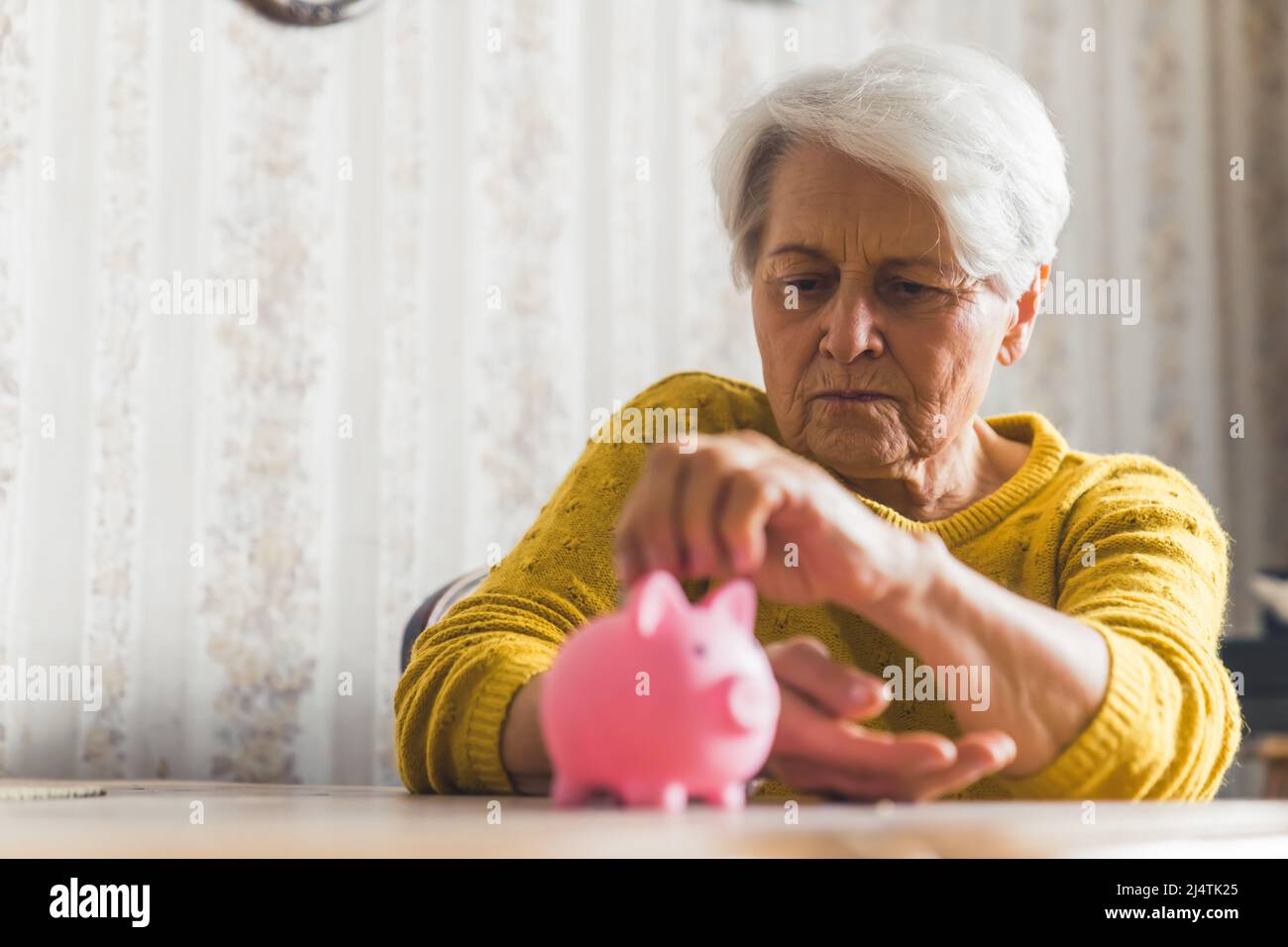 Medium indoor shot of an elderly short-haired woman in a yellow sweater ...
