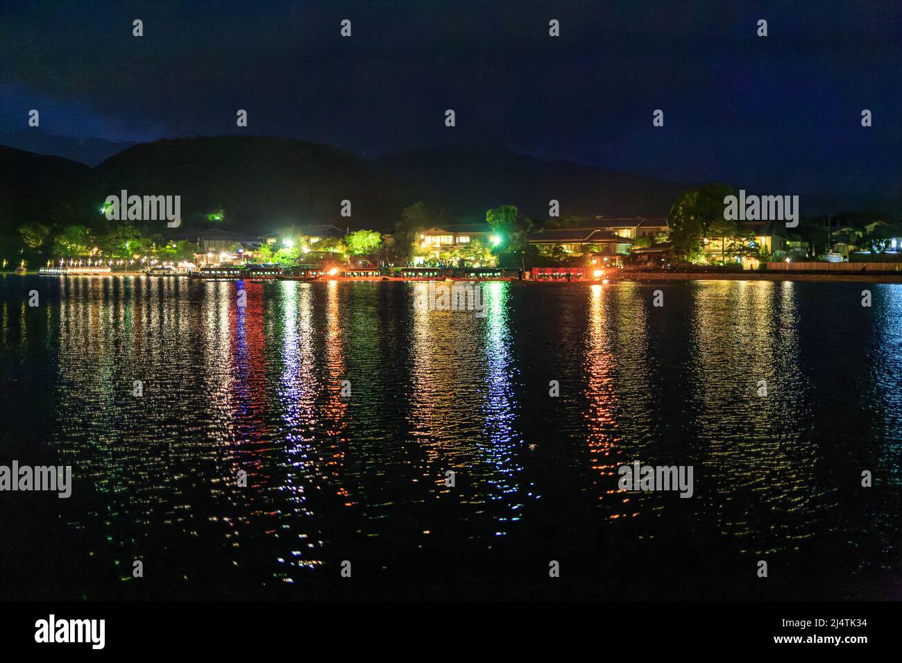 Lights from small shops reflect off river at night Stock Photo Alamy