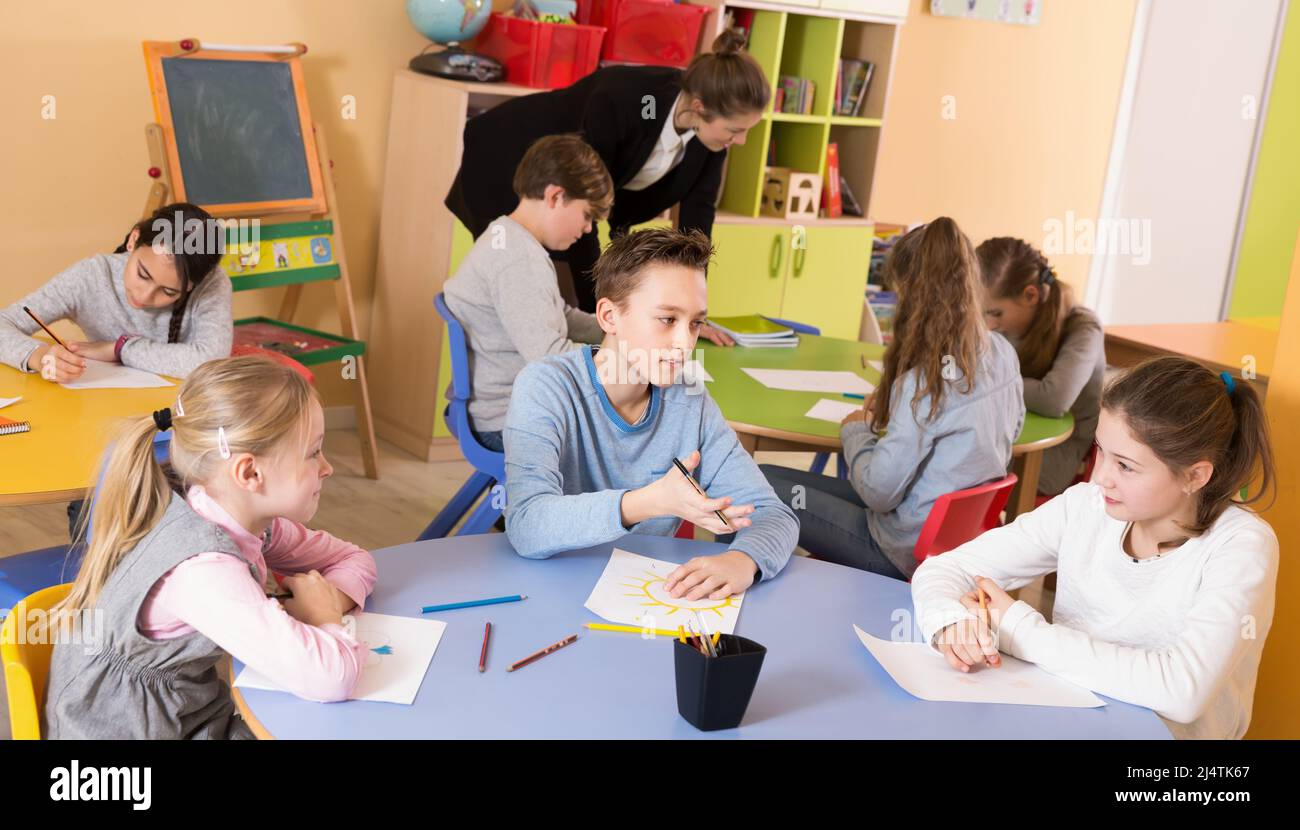 Pupil elementary age drawing at classroom with teacher Stock Photo - Alamy