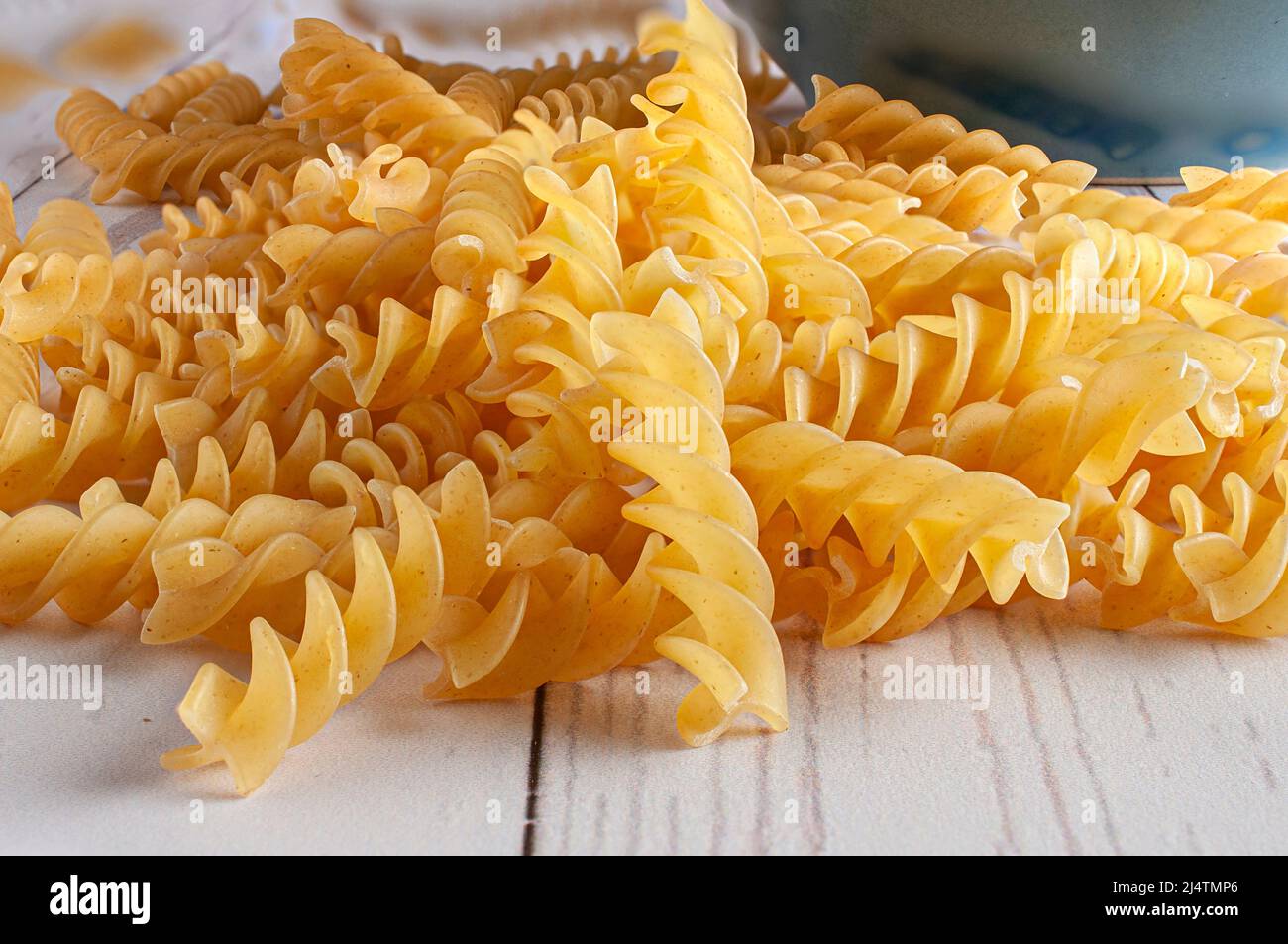 Raw or uncooked fusilli, screw pasta on a white wooden table with a