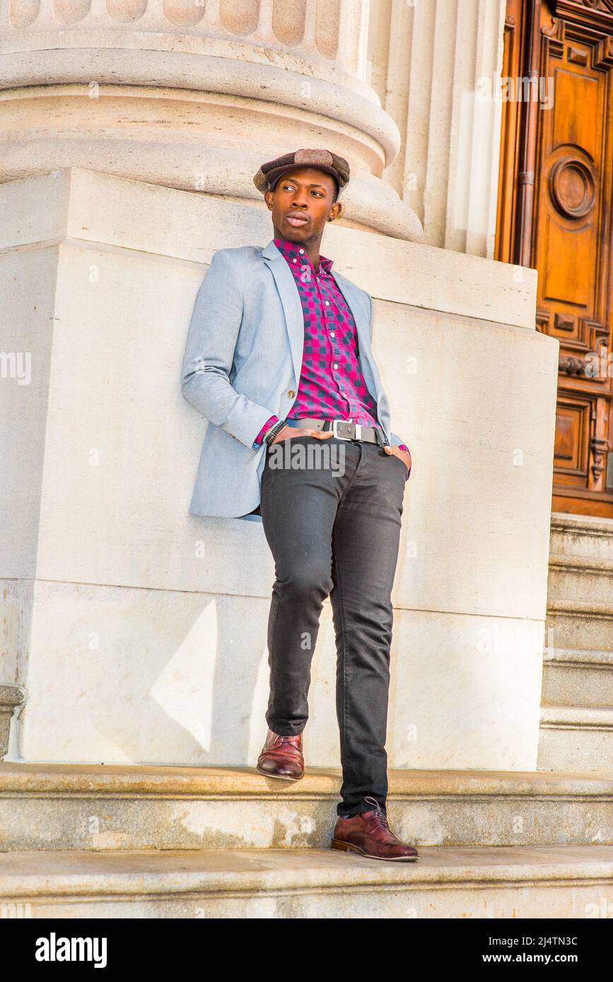 Man Urban Fashion. Wearing a  Newsboy cap, dressing in light gray blazer, patterned pink, black under shirt, black pants, brown leather shoes, a young Stock Photo