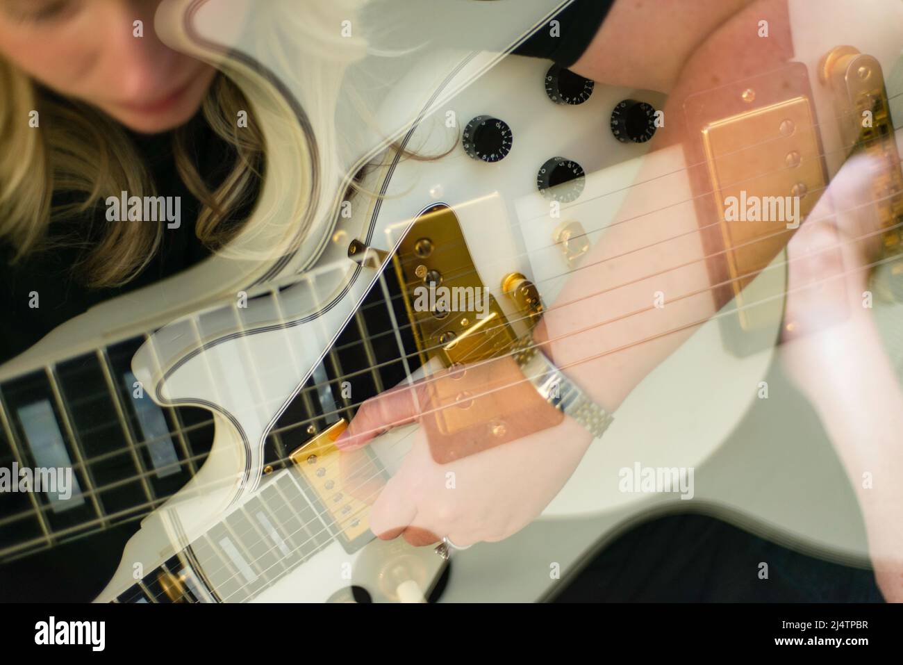 Multi-exposure with blonde singer songwriter woman playing a white Gibson guitar. Stock Photo
