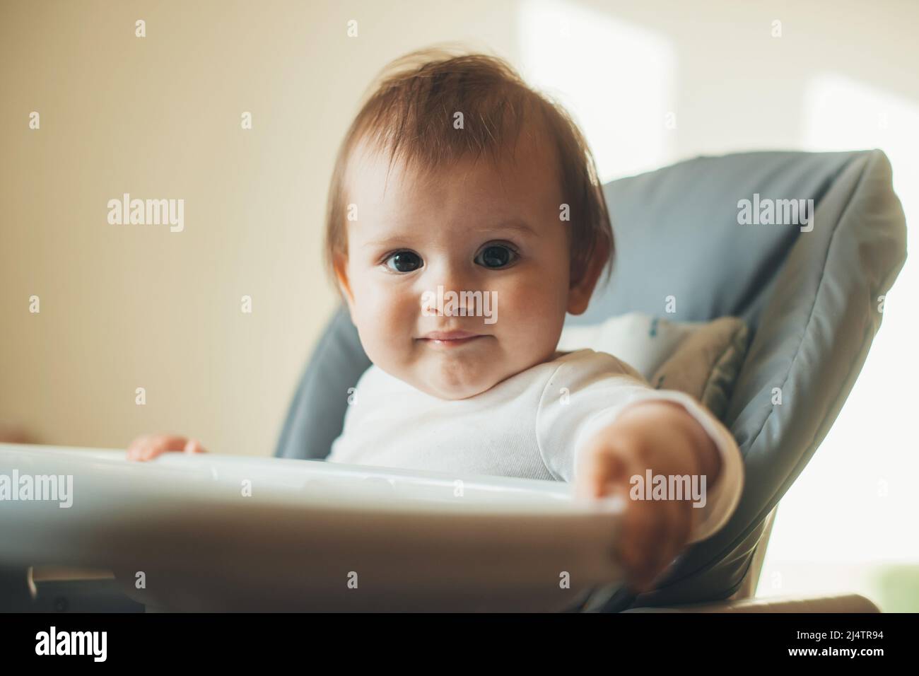 Adorable baby girl sitting in a high chair and smiling, ready for