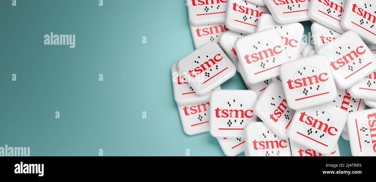 Logos of the Taiwan Semiconductor Manufacturing Company on a heap on a table. Copy space. Web banner format. Stock Photo