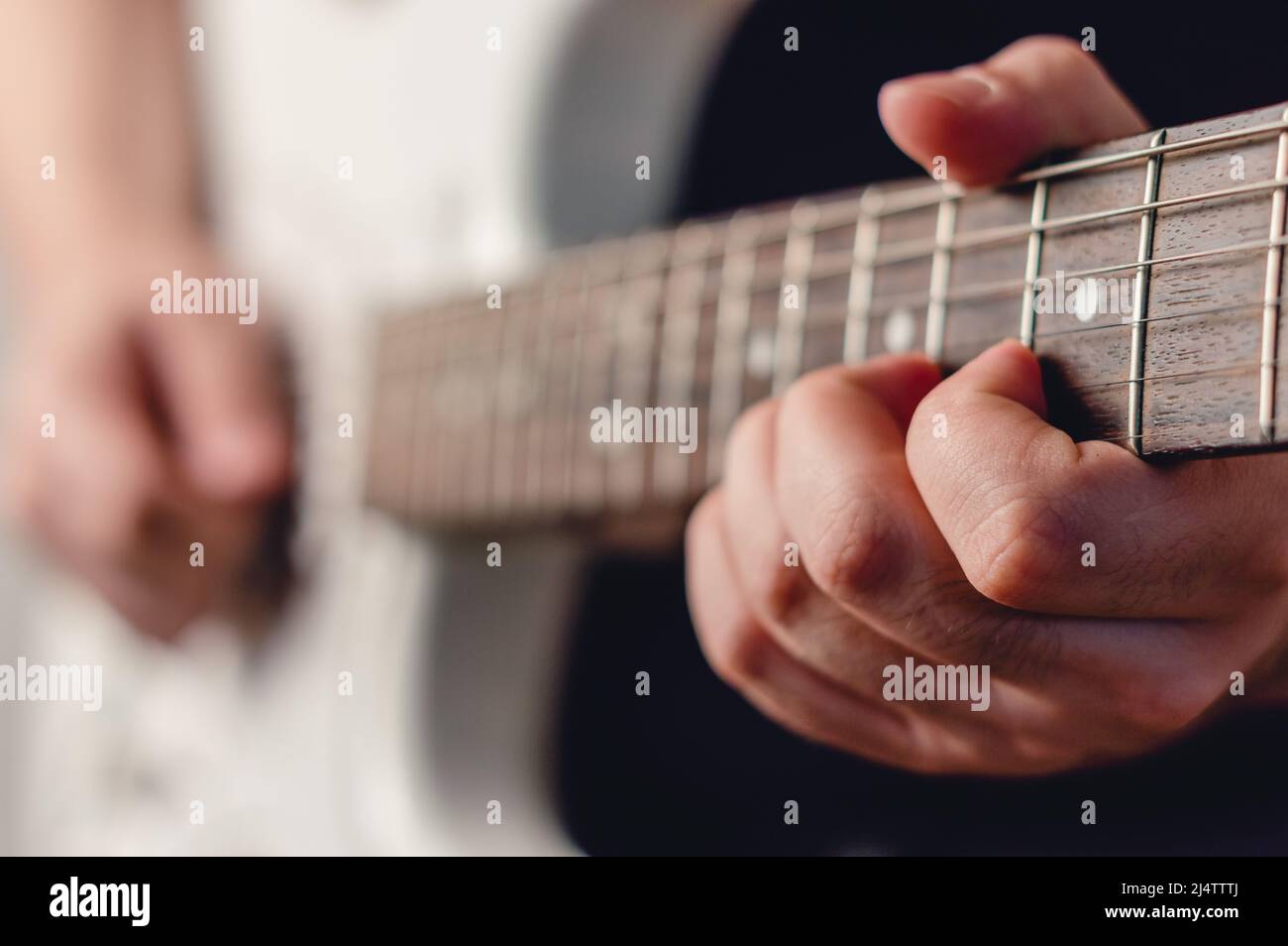 close up caucasian male hand playing white electric guitar making a chord, focus on left hand, music concept, copy space Stock Photo