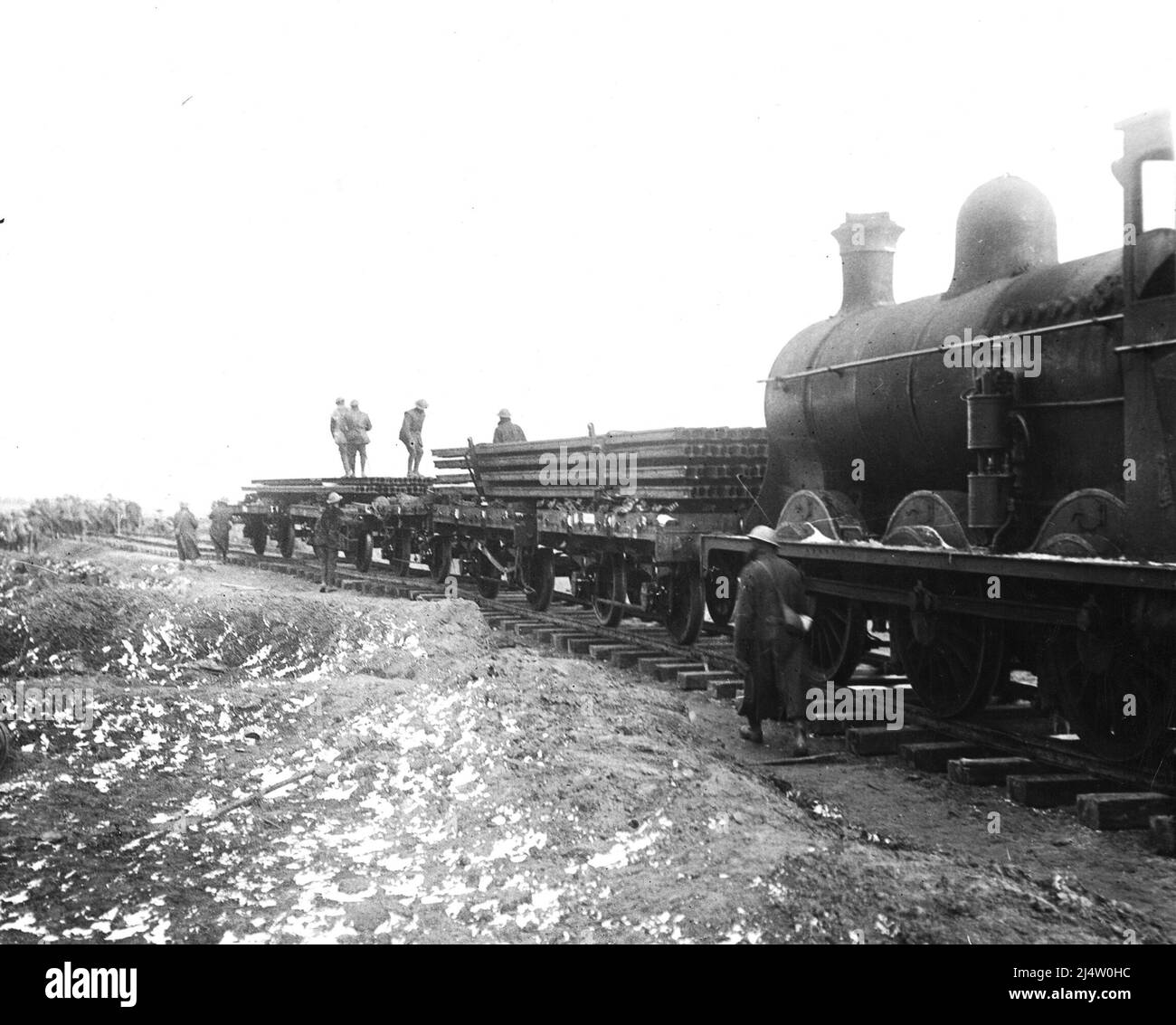Railway lines being laid. A steam engine is shunting carriages full of