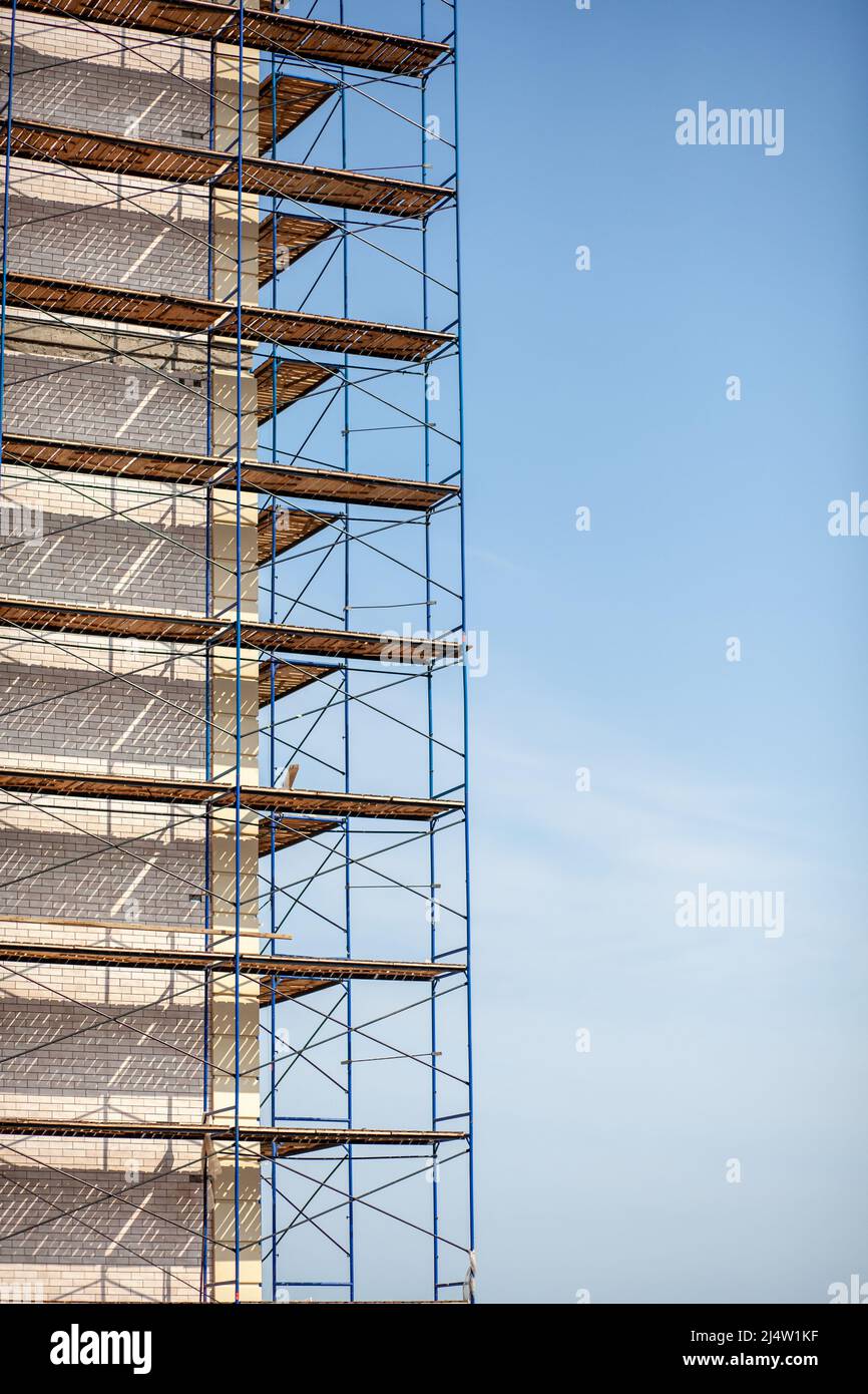 Scaffolding, metal mobile scaffold aginst blue sky background. Modern building is under construction, metal scaffolding. Stock Photo