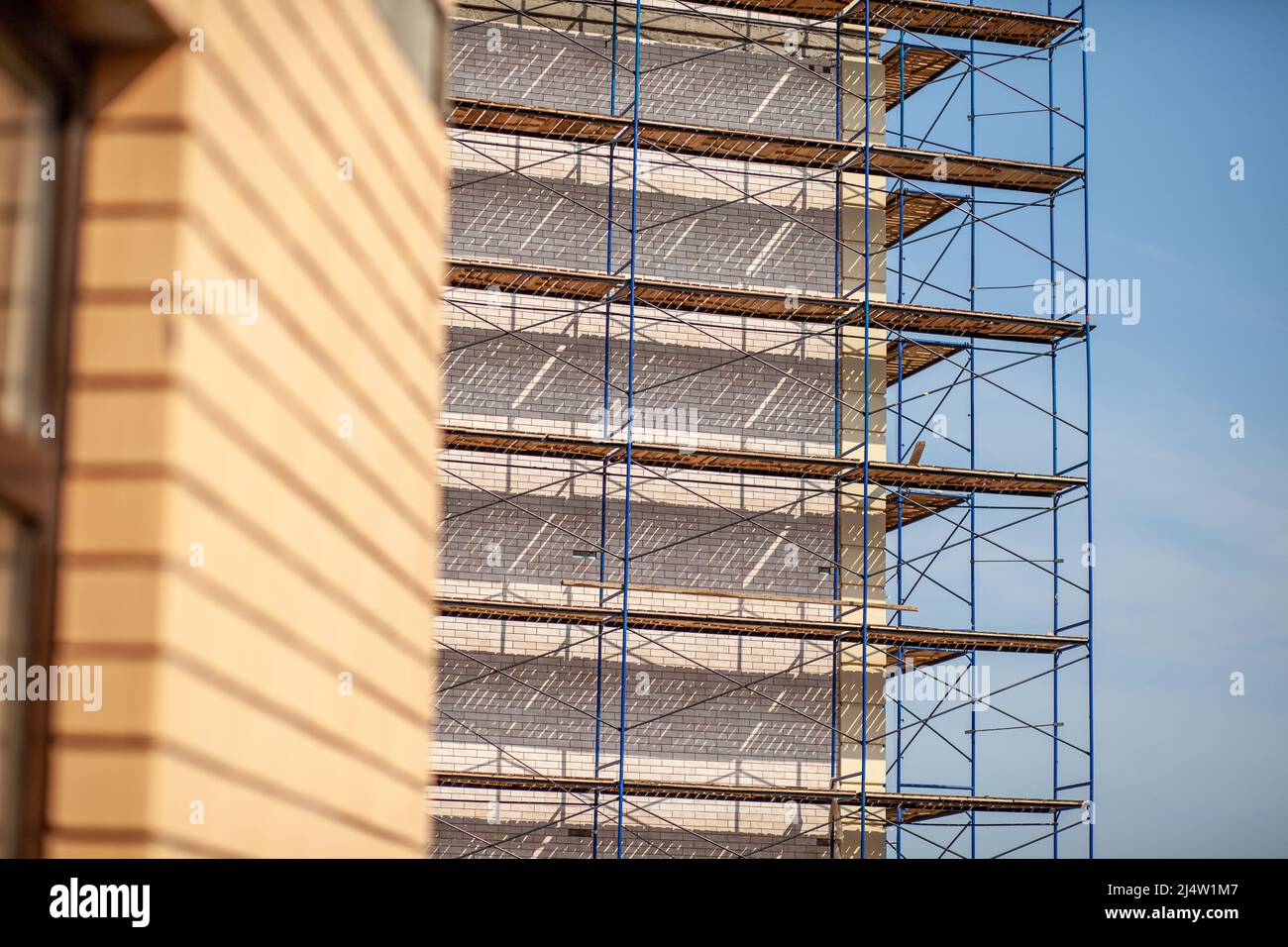 Scaffolding, metal mobile scaffold aginst blue sky background. Modern building is under construction, metal scaffolding. Stock Photo