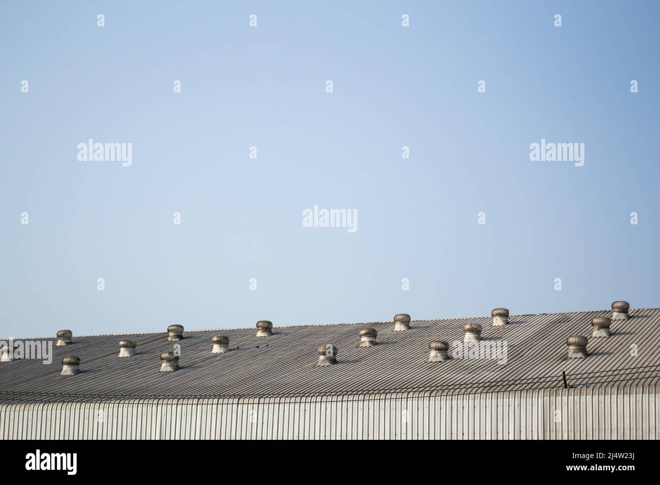 Factory metal roof with ventilator on blue sky Stock Photo
