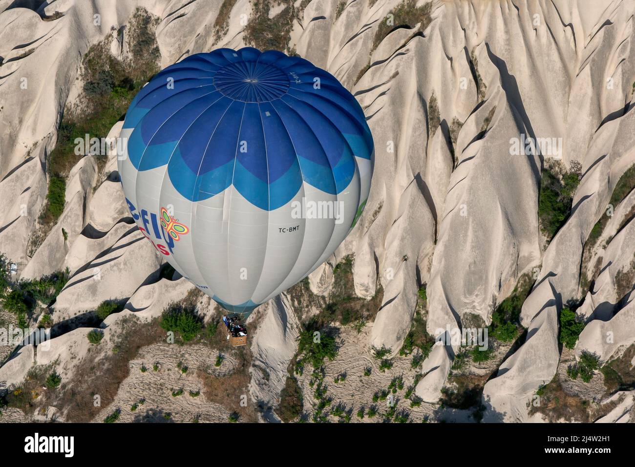 A hot air balloon flying over the incredible landscape near Goreme in the Cappadocia region of Turkey. Stock Photo