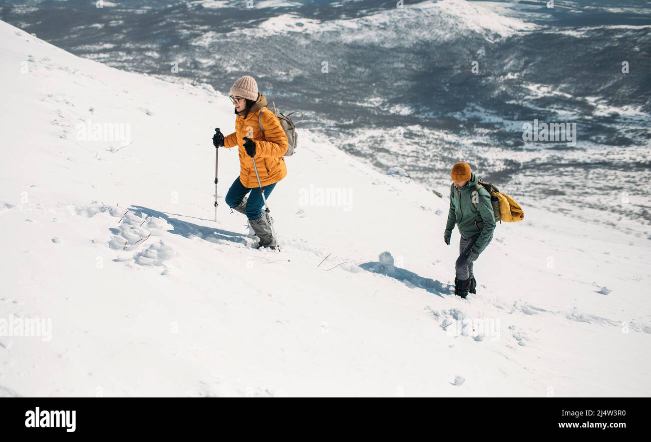 Hiking couple ascending snowy mountain Stock Photo