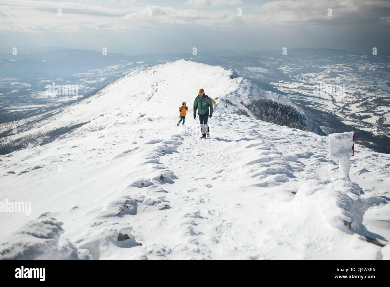 Hiking couple ascending snowy mountain Stock Photo