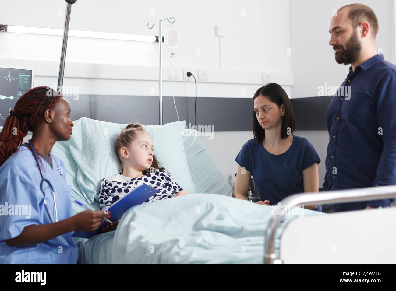 Worried young parents listening to african american nurse talking about consultation results of ill little girl. Healthcare pediatric clinic nurse doing checkup on unwell daughter. Stock Photo
