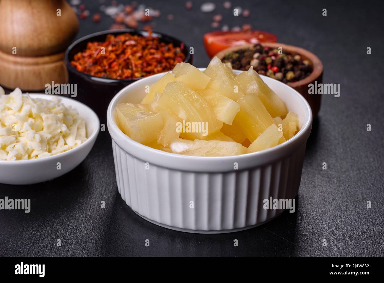 Canned pineapple chunks. Pineapple pieces on dark background Stock