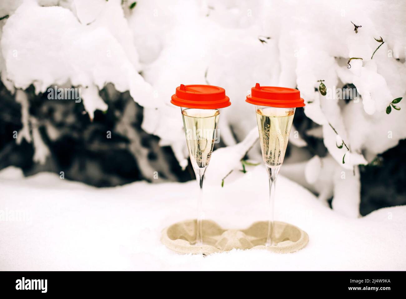 Happy New Year. Two glasses of champagne with red cups standing in snowy courtyard of apartment building. Winter holidays concept Stock Photo