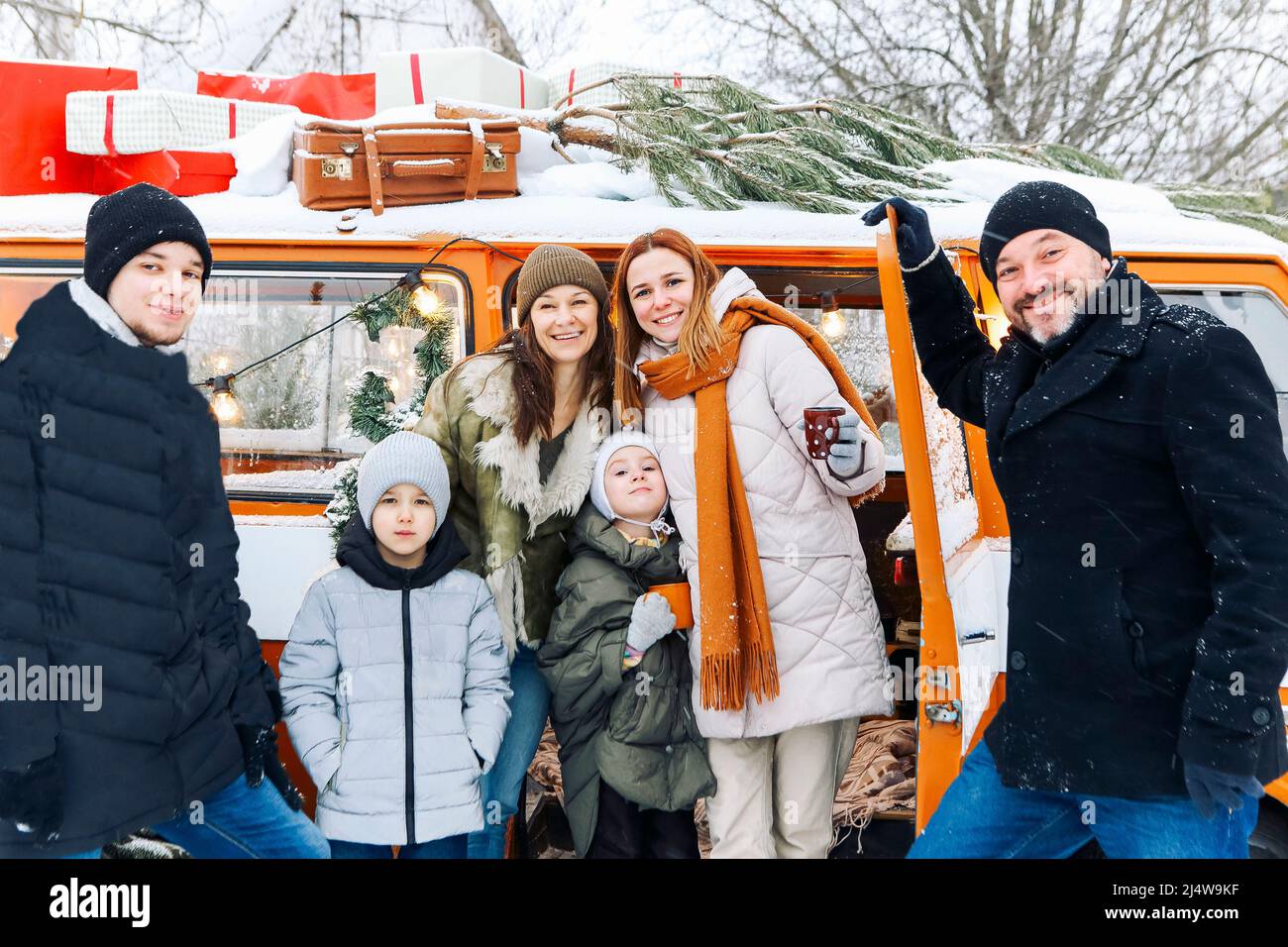 Happy family of travelers in minivan lying together at open rear doors and smiling at camera. Joyful group of people traveling winter snowy nature, sp Stock Photo