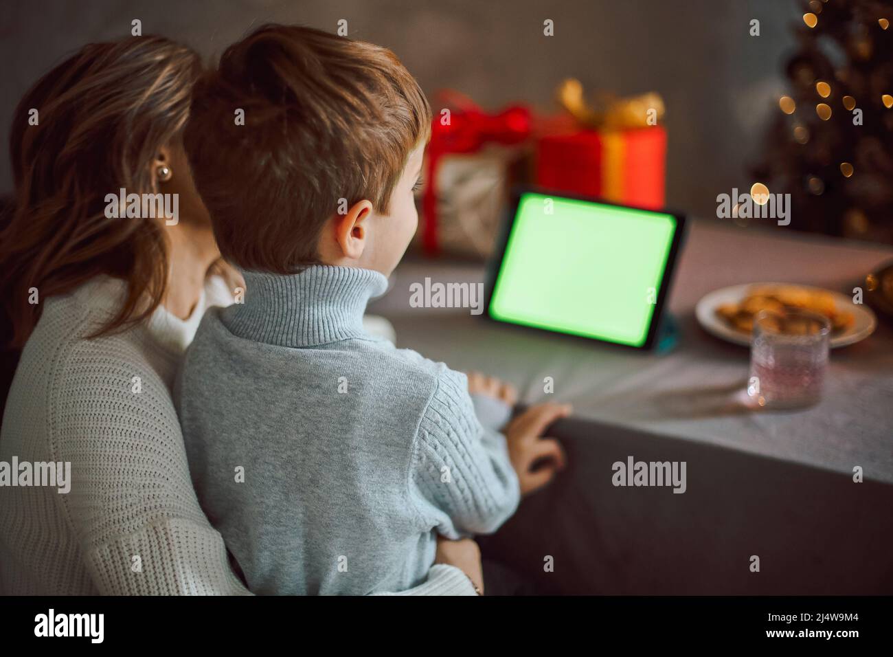 Happy young woman with little son, talking with friends on virtual zoom video call, celebrating new year party in holiday remote online conference cha Stock Photo