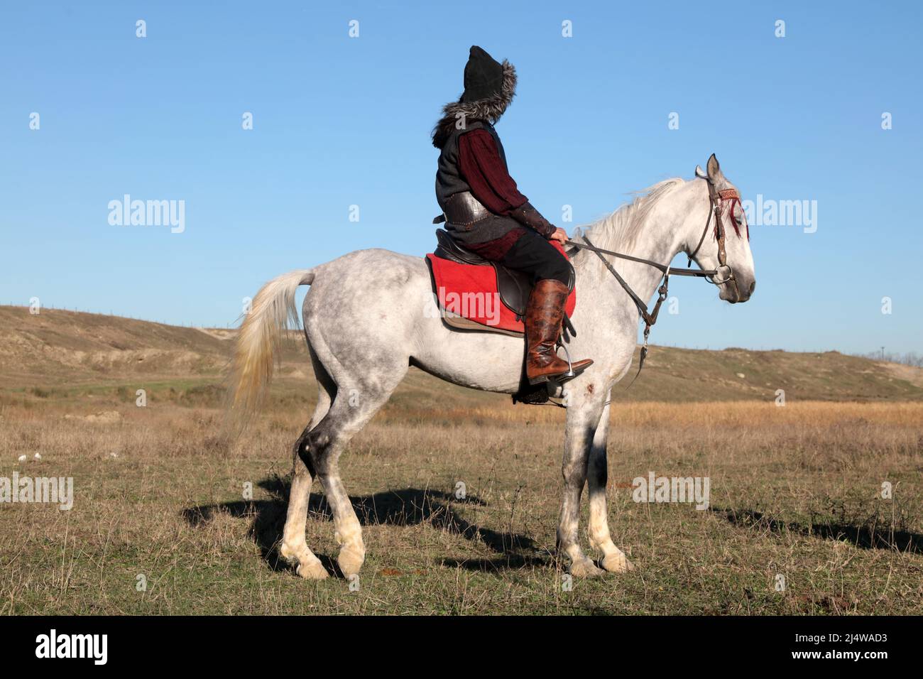 A Turkish soldier in traditional clothing is riding a white horse. An