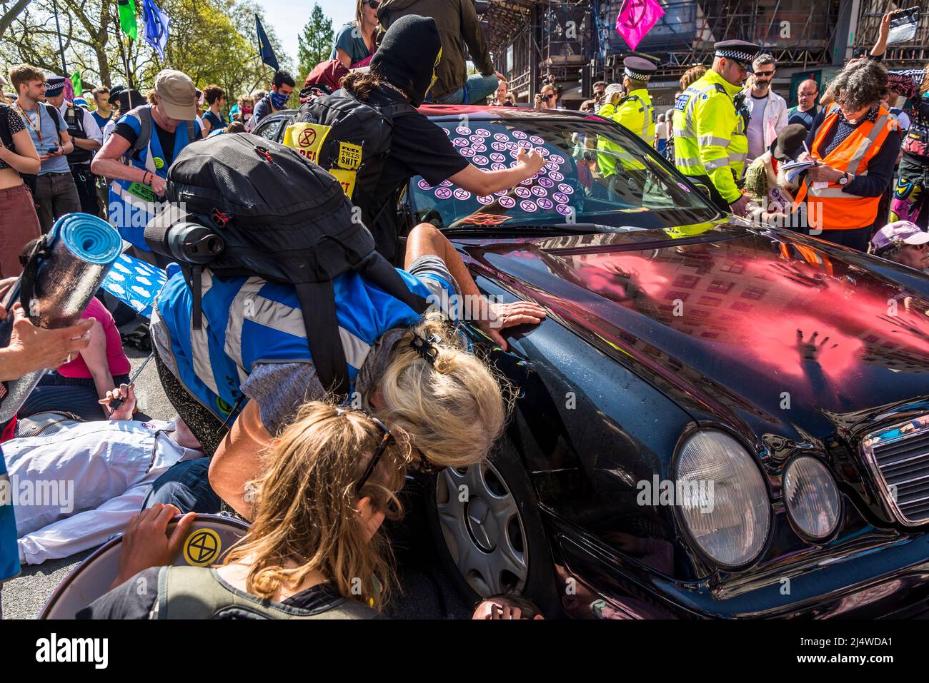 Activists stopping a car by lying around it and man putting XR stickers on the car, We Will Not Be Bystanders, an Extinction Rebellion protest that fi Stock Photo