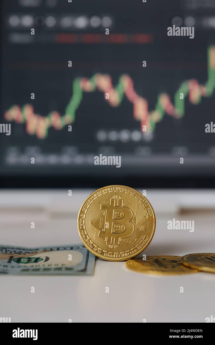 Gold bitcoin crypto currency and US dollars on background of tablet with stock diagram. Investment in virtual money. Cryptocurrency concept Stock Photo