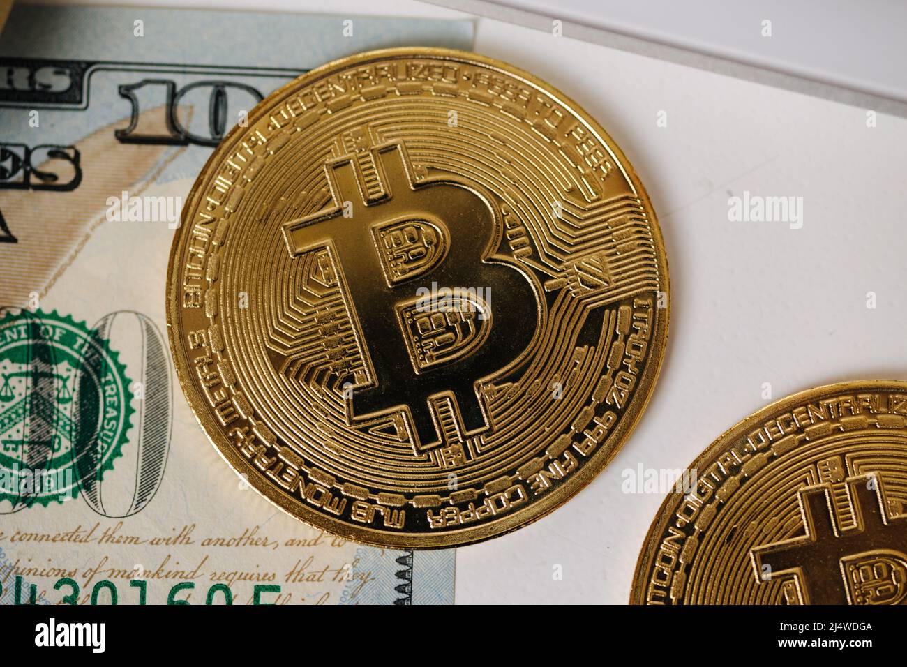 Close-up of golden shiny bitcoin crypto currency coins on one hundred US dollar bills. Difference between cryptocurrencies and cash Stock Photo