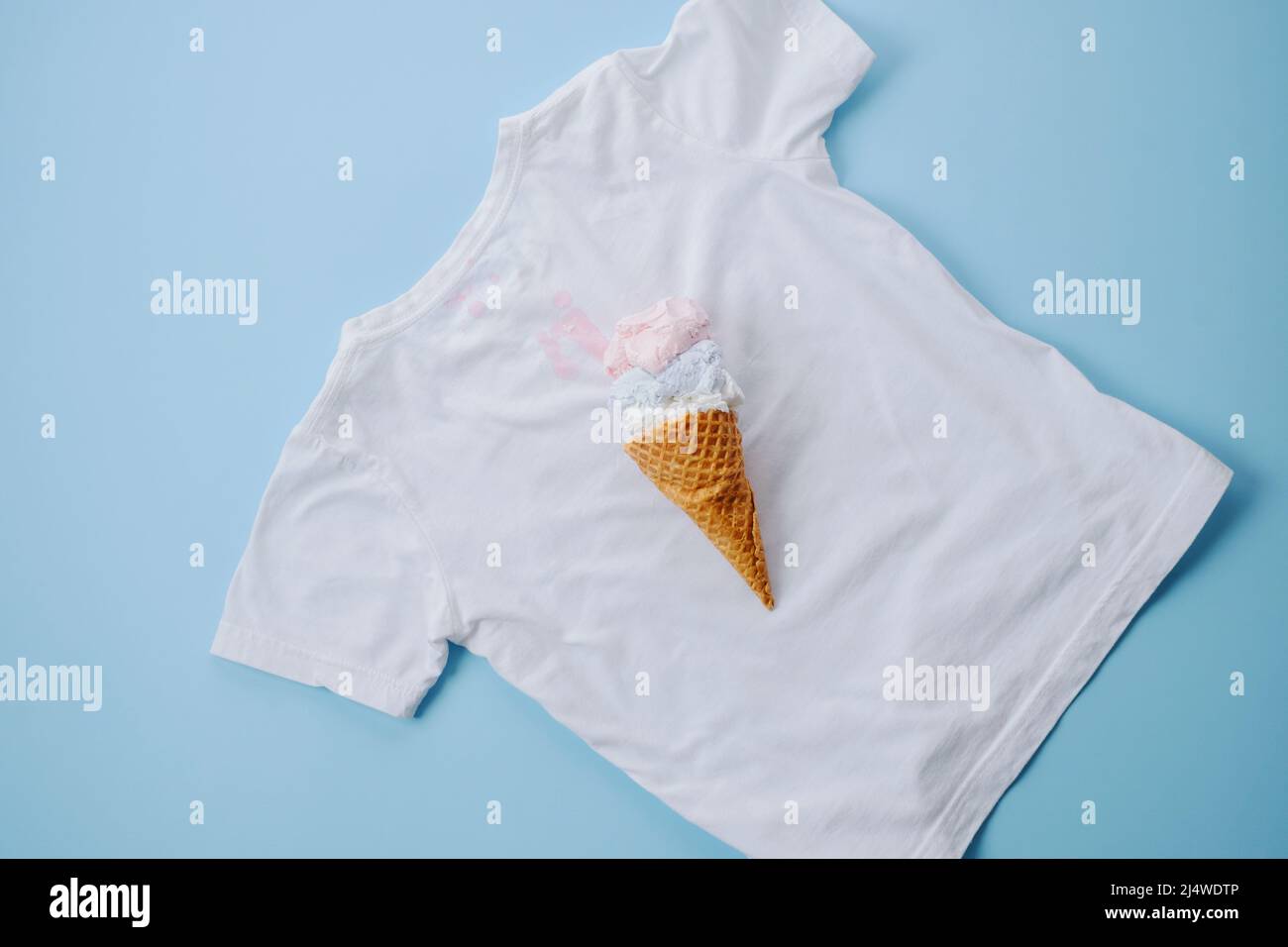 Dirty stain ice cream on white clothes on a blue background. top view