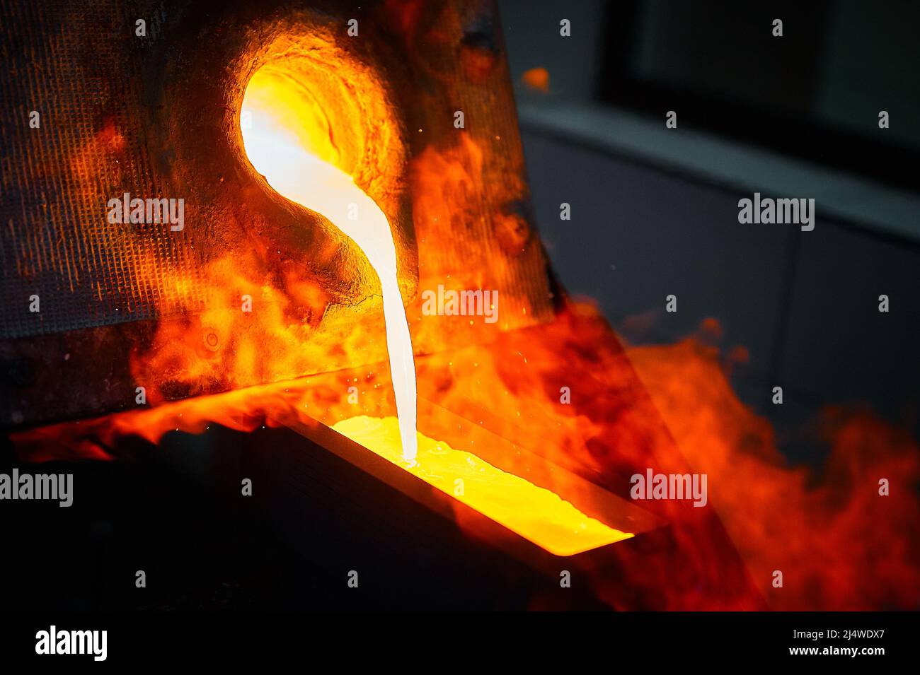 Pouring liquid gold into graphite casting form from furnace Stock Photo