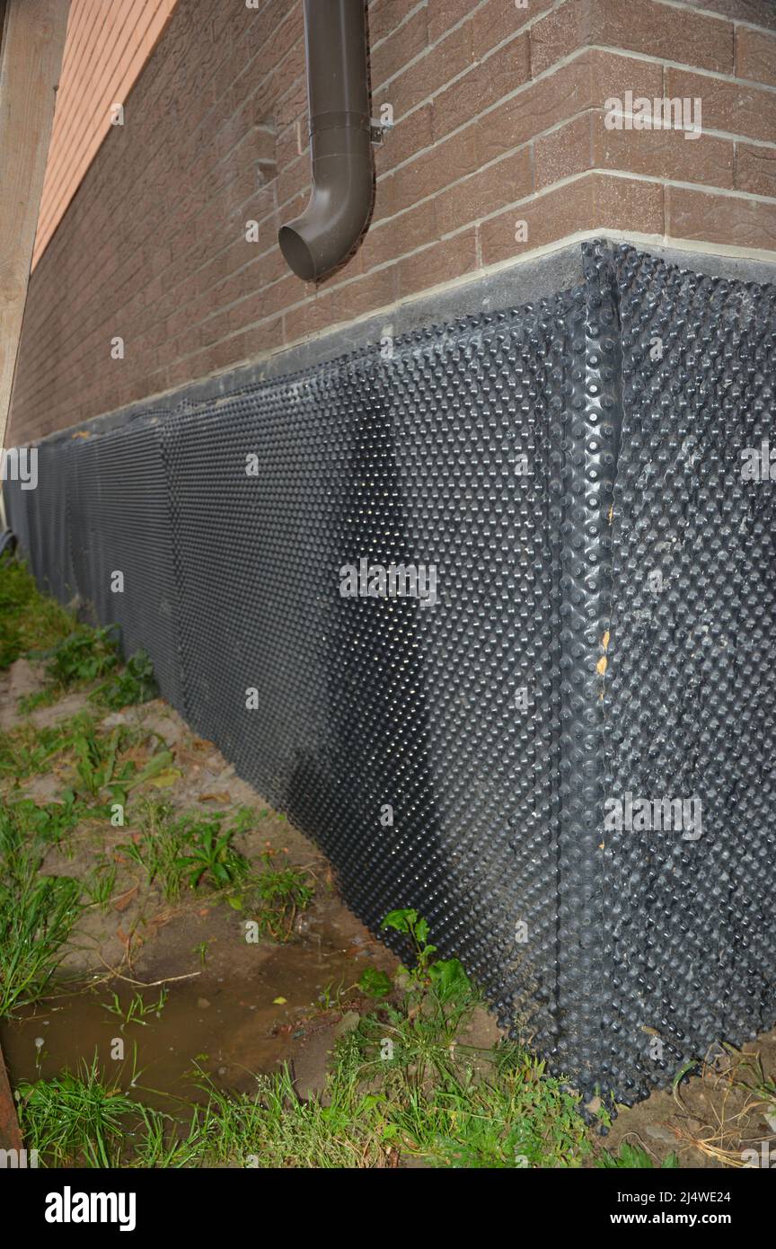 A closeup of a wet house foundation waterproofing because of a gutter