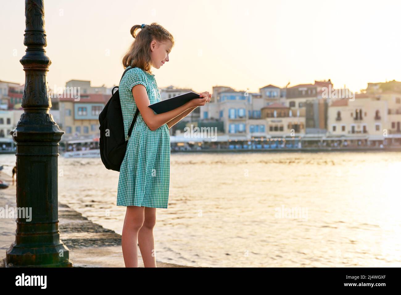 Girl child young student with backpack reading school notebook, outdoor ...