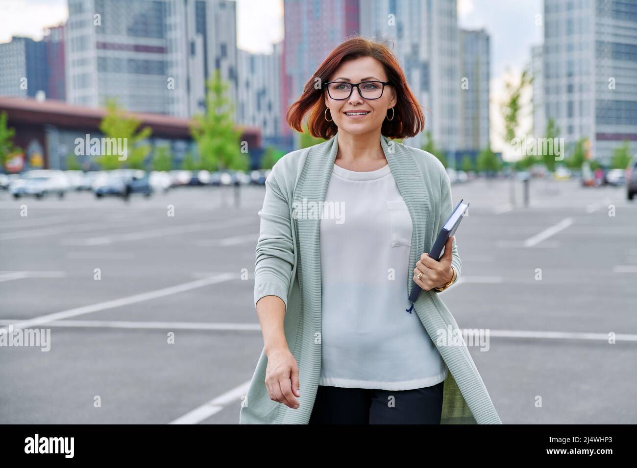 Smiling successful mature business woman walking outdoor, modern urban style background. Stock Photo