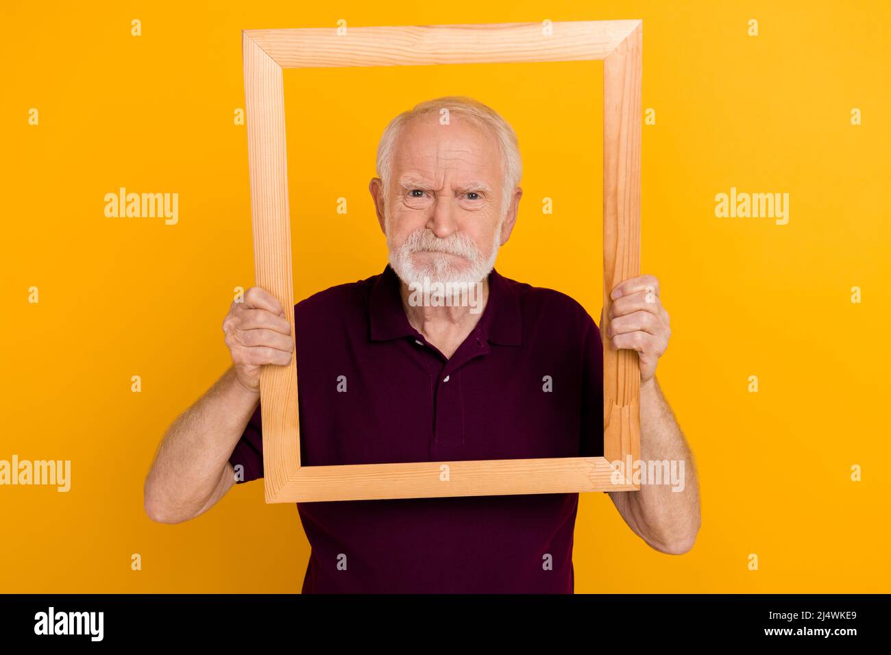 Photo of mature man hold wood frame moody frowning take album shots isolated over yellow color background Stock Photo