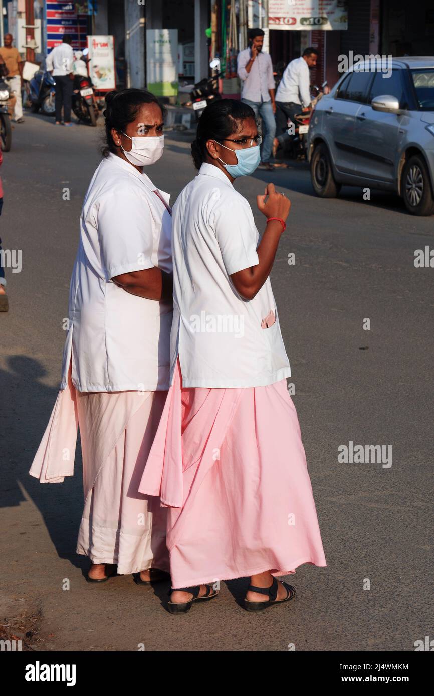 Two young hospital nurses waiting to cross the road in Trichy, Tamil Nadu, India Stock Photo