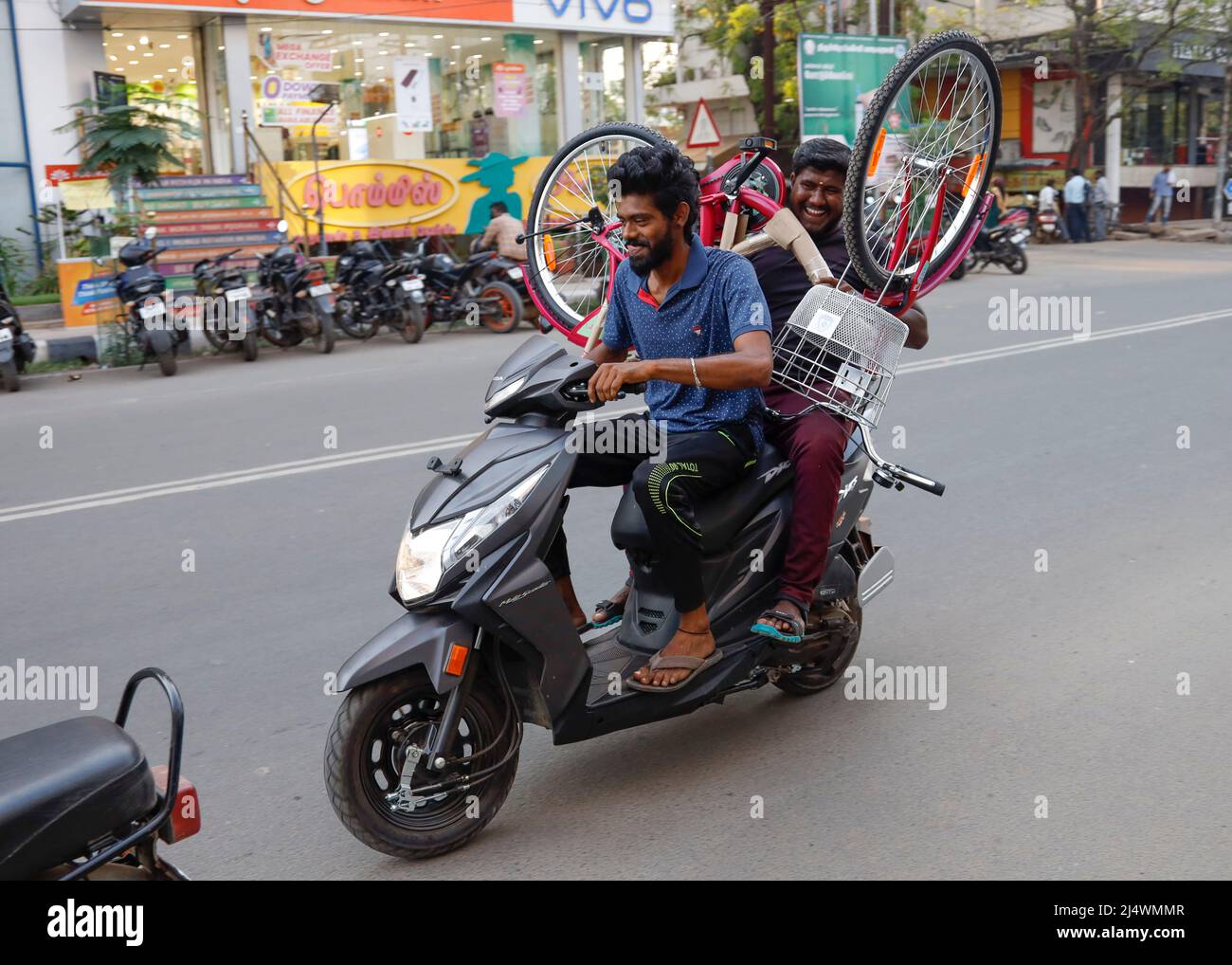 Men riding a scooter carrying a bicycle in Trichy, Tamil Nadu