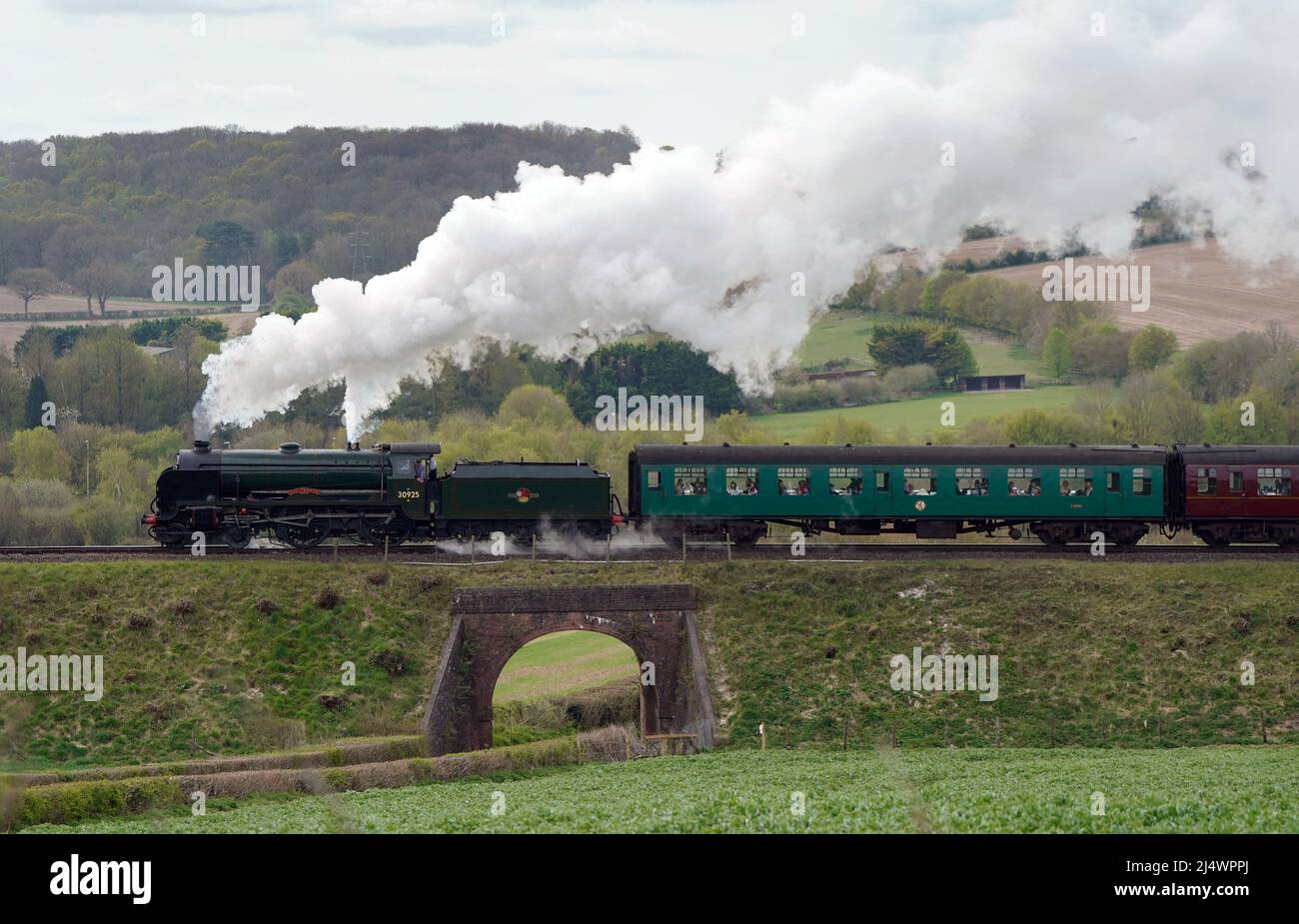 The SR V Schools class steam locomotive Cheltenham makes it's way along the Mid Hants Railway, also known as the Watercress line, near to Ropley in Hampshire. Picture date: Monday April 18, 2022. Stock Photo