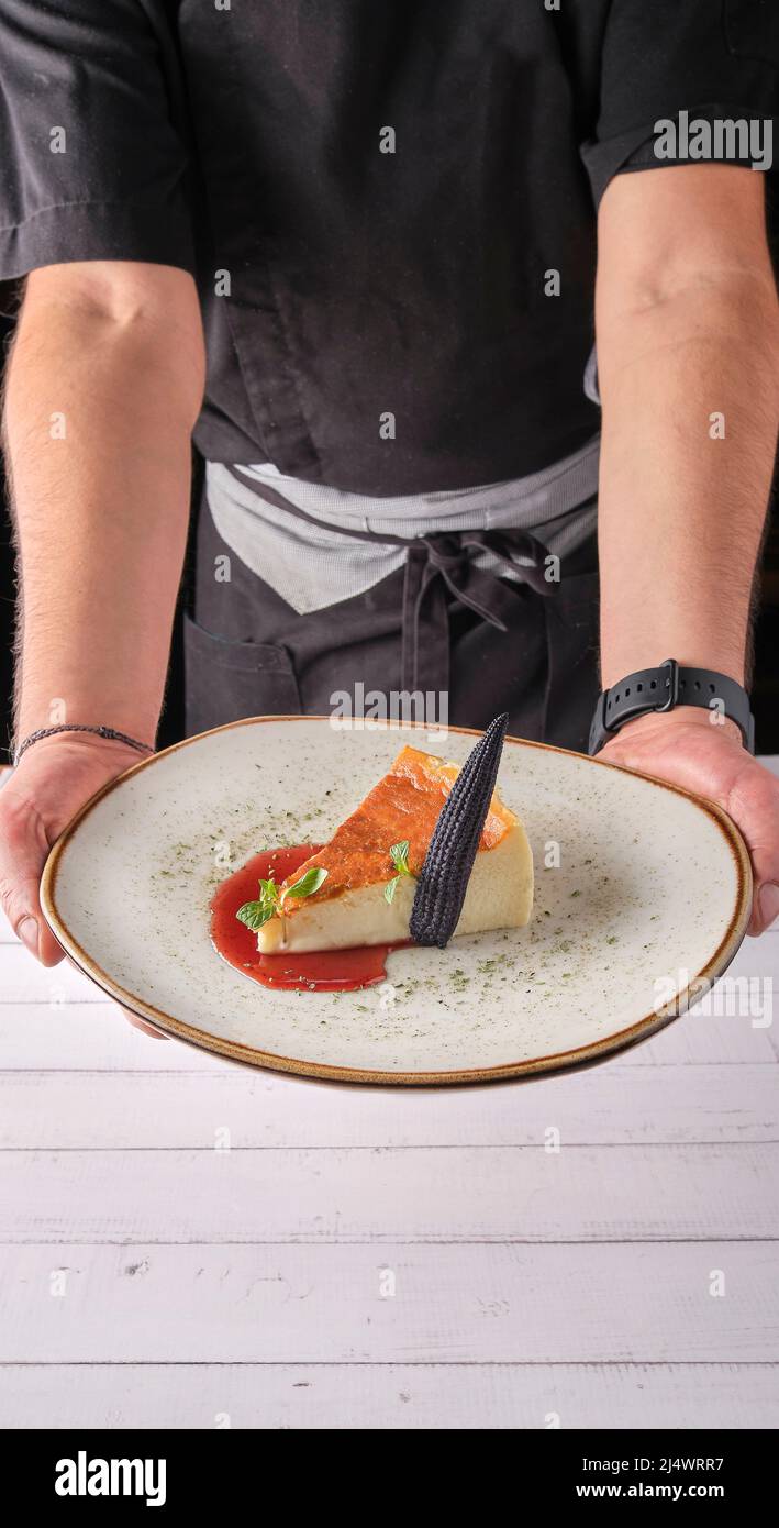 Chef presenting plate of New York cheesecake or classic cheesecake with fresh, appetizing healthy. Stock Photo