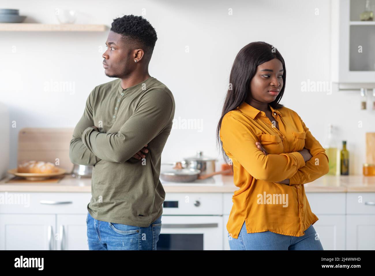 Young Black Couple Standing Back To Back To Each Other In Kitchen Stock Photo