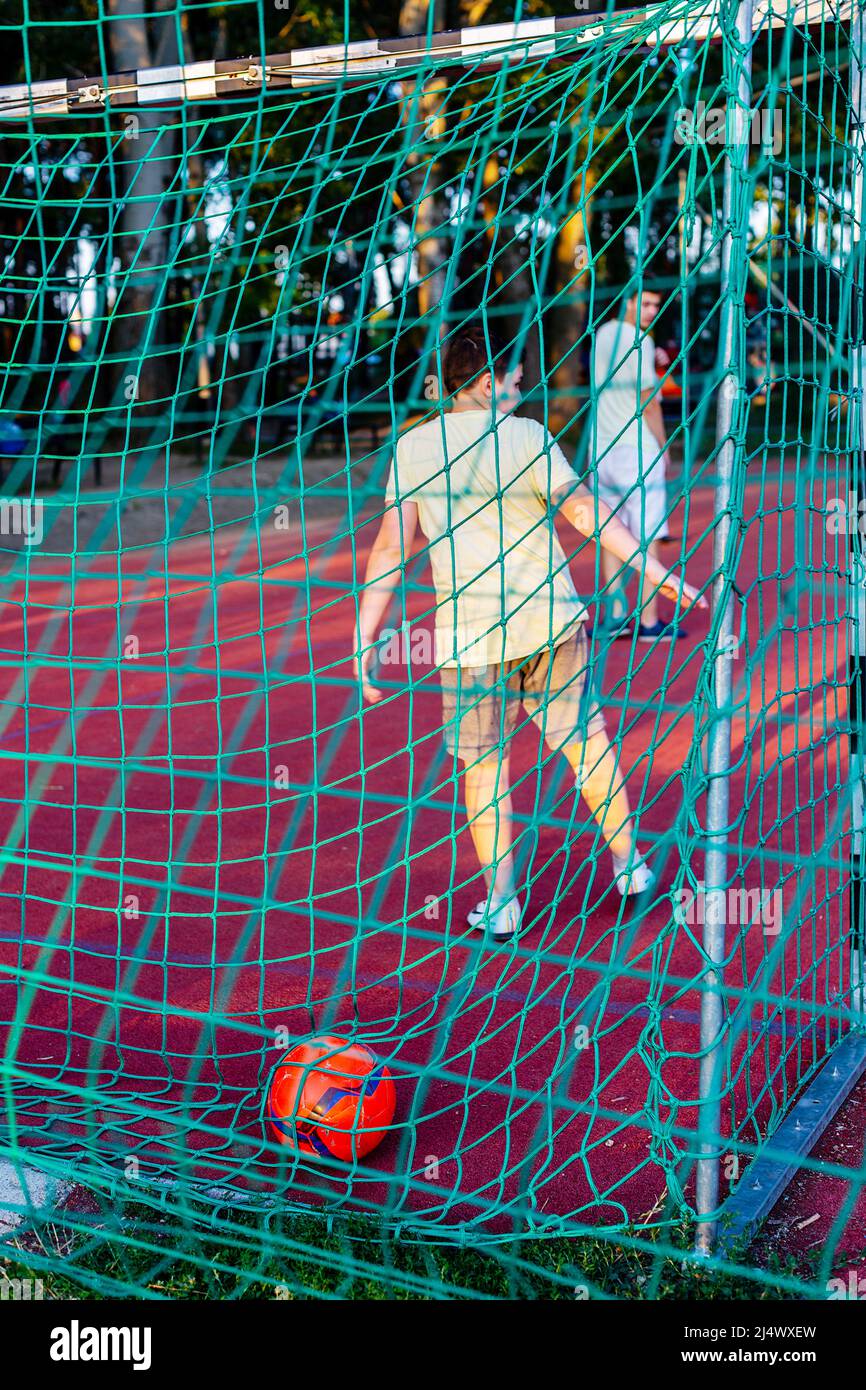 Nyiregyhaza, Hungary – July 15, 2019: Ball in goal, missed goal, confused boy as soccer goalkeeper  standing at the gates. Selective focus, focus on b Stock Photo