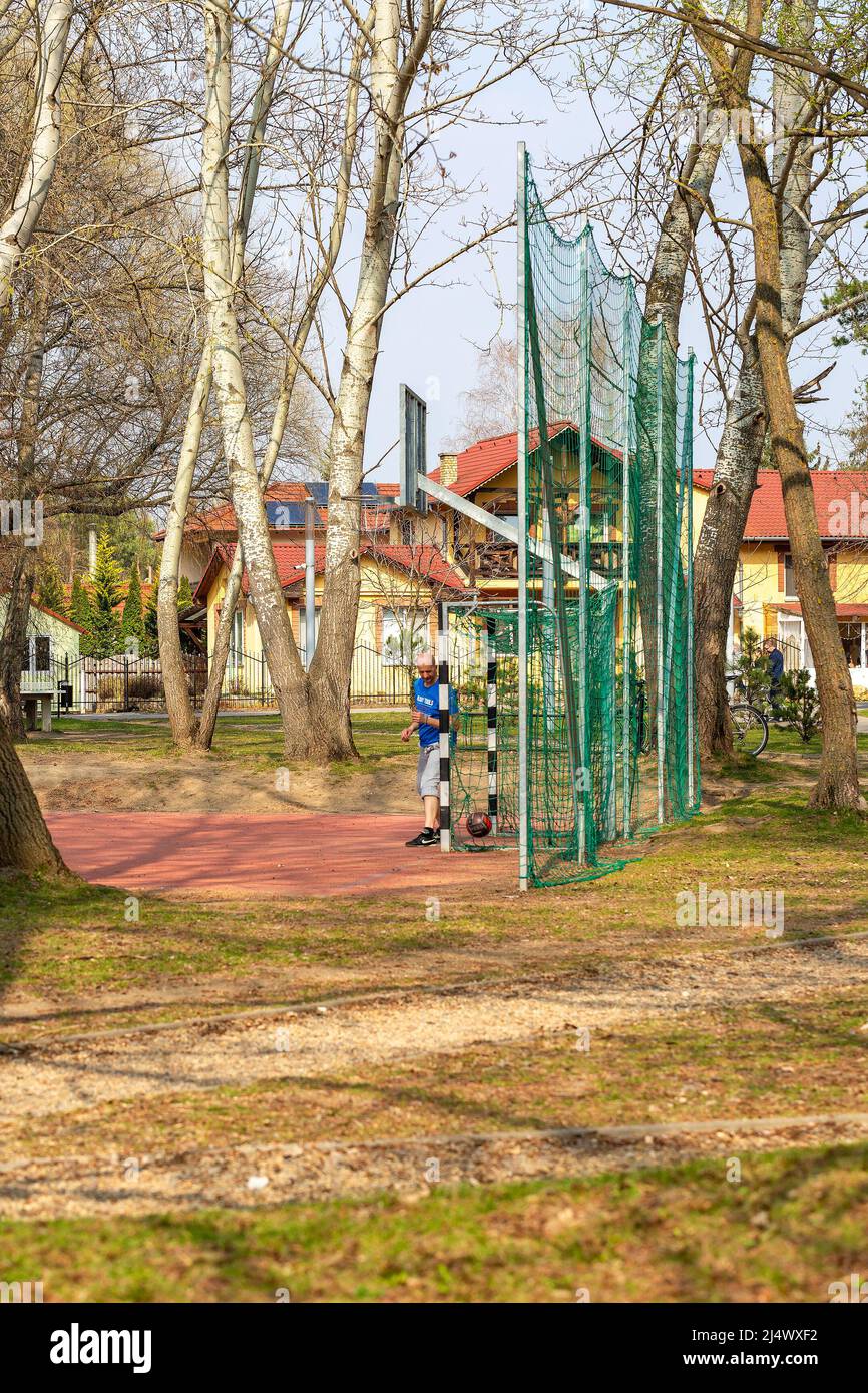 Nyiregyhaza, Hungary – March 24, 2019: Football field in public park. Ball not in goal, man as soccer goalkeeper  standing at the gates Stock Photo