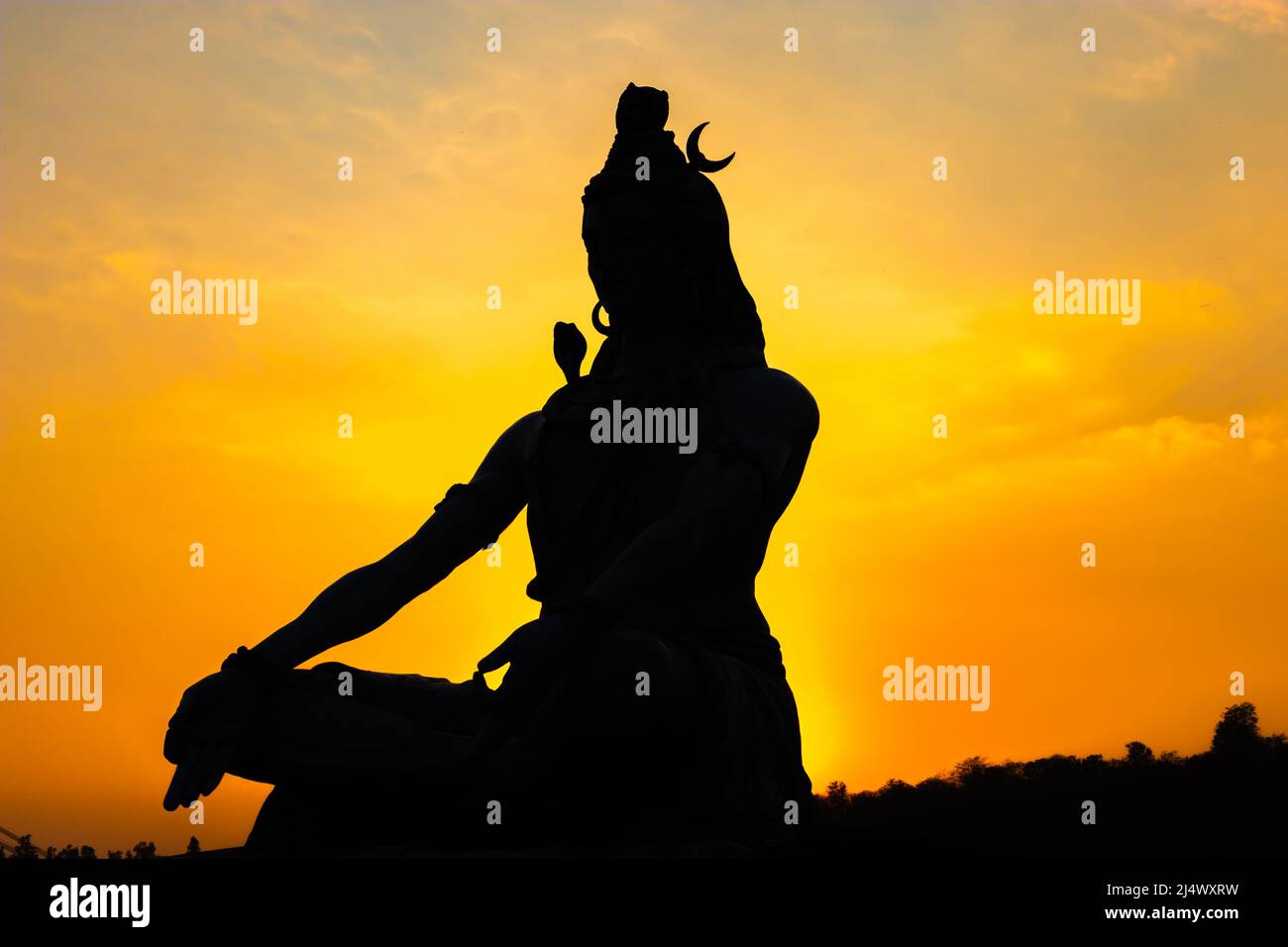 back lit statue of hindu god lord shiva in meditation posture with dramatic sky from unique angle image is taken at parmarth niketan rishikesh uttrakh Stock Photo