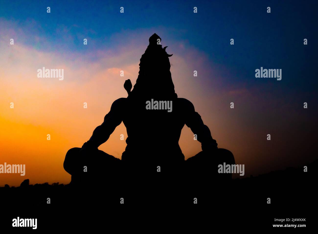 back lit statue of hindu god lord shiva in meditation posture with dramatic sky from unique angle image is taken at parmarth niketan rishikesh uttrakh Stock Photo